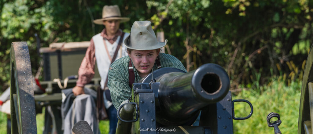 A female soldier aiming a cannon, focused and determined as she adjusts the weapon's position. Dressed in military attire, she embodies strength and resolve, demonstrating the critical role of women in artillery during wartime. The scene highlights her concentration and the importance of teamwork in preparing for fire.